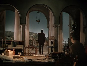 Movie still from “Pandora and the Flying Dutchman” (1951), directed by Albert Lewin – A man in a suit standing in front of an arched doorway; Wide shot, High angle
