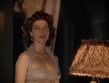 Movie still from “Pandora and the Flying Dutchman” (1951), directed by Albert Lewin – A woman standing next to a lamp in a dark room; Close Up shot, Low angle