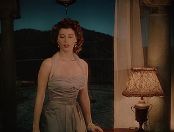Movie still from “Pandora and the Flying Dutchman” (1951), directed by Albert Lewin – A woman standing in front of a lamp and a window; Medium shot, Low angle