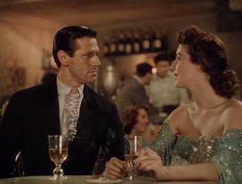 Movie still from “Pandora and the Flying Dutchman” (1951), directed by Albert Lewin – A man and a woman sitting at a table with wine glasses; Medium shot, Over the shoulder angle