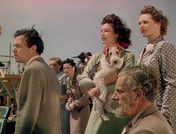 Movie still from “Pandora and the Flying Dutchman” (1951), directed by Albert Lewin – A group of people standing next to each other with a dog; Medium shot, High angle