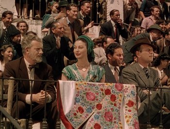 Movie still from “Pandora and the Flying Dutchman” (1951), directed by Albert Lewin – A woman sitting in front of a group of people; Medium shot, High angle