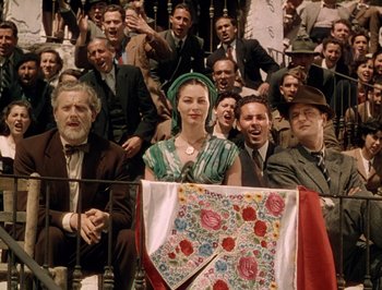 Movie still from “Pandora and the Flying Dutchman” (1951), directed by Albert Lewin – A group of people sitting in front of a flag; Wide shot, Low angle