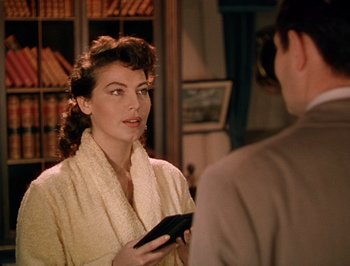 Movie still from “Pandora and the Flying Dutchman” (1951), directed by Albert Lewin – A woman holding a cell phone while standing next to a man; Medium shot, Over the shoulder angle