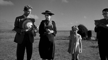 Movie still from “Paper Moon” (1973), directed by Peter Bogdanovich – A black and white photo of a woman and two men and a girl; Wide shot, Over the shoulder angle