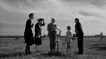 Movie still from “Paper Moon” (1973), directed by Peter Bogdanovich – A group of people standing in a grassy field; Wide shot, Low angle