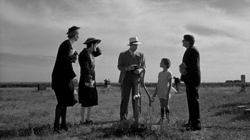 Movie still from “Paper Moon” (1973), directed by Peter Bogdanovich – A group of people standing in a grassy field; Wide shot, Low angle