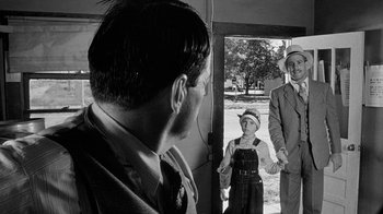 Movie still from “Paper Moon” (1973), directed by Peter Bogdanovich – A black and white photo of a man and two women; Medium shot, Over the shoulder angle