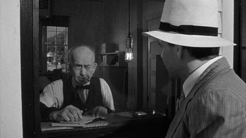 Movie still from “Paper Moon” (1973), directed by Peter Bogdanovich – An old man sitting at a table with a man wearing a white hat; Close Up shot, Over the shoulder angle