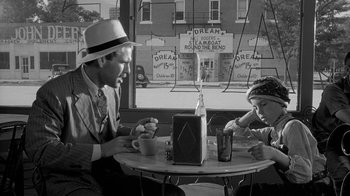 Movie still from “Paper Moon” (1973), directed by Peter Bogdanovich – A man sitting at a table with a young girl; Medium shot, Over the shoulder angle