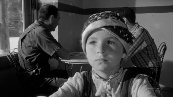 Movie still from “Paper Moon” (1973), directed by Peter Bogdanovich – A young boy wearing an american flag hat in front of two other people; Close Up shot, Over the shoulder angle
