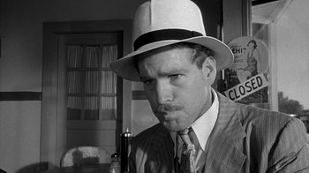 Movie still from “Paper Moon” (1973), directed by Peter Bogdanovich – A black and white photo of a man in a suit and a hat; Close Up shot, Over the shoulder angle