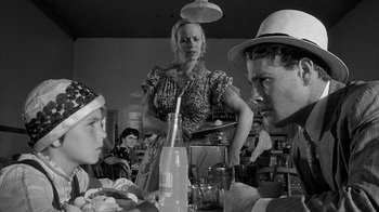 Movie still from “Paper Moon” (1973), directed by Peter Bogdanovich – A group of people sitting around a table; Medium shot, Over the shoulder angle