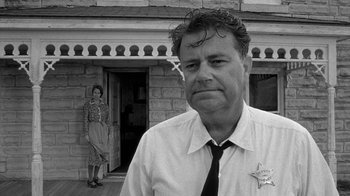 Movie still from “Paper Moon” (1973), directed by Peter Bogdanovich – A man and woman standing in front of a brick building; Medium shot, Low angle