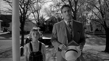 Movie still from “Paper Moon” (1973), directed by Peter Bogdanovich – A man and a boy standing next to each other in front of trees; Medium shot, Low angle