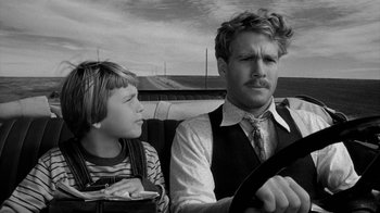 Movie still from “Paper Moon” (1973), directed by Peter Bogdanovich – A man and a boy sitting in the back seat of a car; Close Up shot, Over the shoulder angle