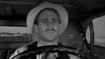 Movie still from “Paper Moon” (1973), directed by Peter Bogdanovich – A black and white photo of a man in a hat driving a car; Close Up shot, Over the shoulder angle