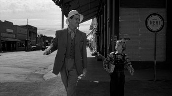 Movie still from “Paper Moon” (1973), directed by Peter Bogdanovich – A man and a boy walking down a street; Wide shot, Over the shoulder angle