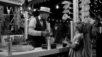 Movie still from “Paper Moon” (1973), directed by Peter Bogdanovich – An old man and a little girl at an amusement park; Medium shot, Low angle