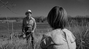 Movie still from “Paper Moon” (1973), directed by Peter Bogdanovich – A man and a woman are standing in a field; Medium shot, Over the shoulder angle