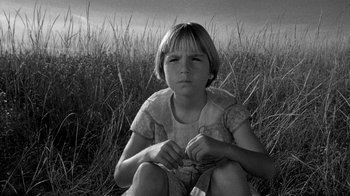 Movie still from “Paper Moon” (1973), directed by Peter Bogdanovich – A young girl sitting in a field of tall dry grass; Close Up shot, High angle