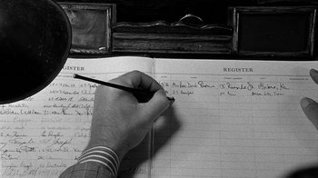 Movie still from “Paper Moon” (1973), directed by Peter Bogdanovich – A person writing in a book on a table; Extreme Close Up shot, High angle