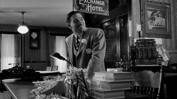 Movie still from “Paper Moon” (1973), directed by Peter Bogdanovich – A man standing in front of a pile of papers; Medium shot, Low angle