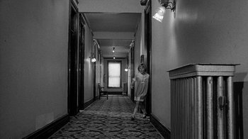 Movie still from “Paper Moon” (1973), directed by Peter Bogdanovich – A woman standing in the hallway of a building; Wide shot, High angle