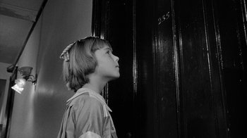 Movie still from “Paper Moon” (1973), directed by Peter Bogdanovich – A young girl standing in front of a wooden door; Close Up shot, Low angle
