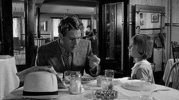 Movie still from “Paper Moon” (1973), directed by Peter Bogdanovich – A man sitting at a dinner table with a girl; Medium shot, Over the shoulder angle