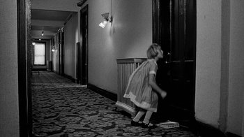 Movie still from “Paper Moon” (1973), directed by Peter Bogdanovich – A little girl in a dress is walking down the hall way; Wide shot, High angle