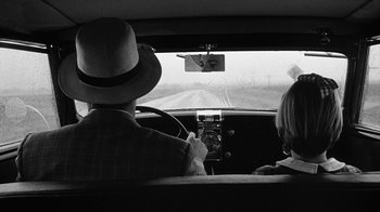 Movie still from “Paper Moon” (1973), directed by Peter Bogdanovich – A man and a woman driving a car on a road; Medium shot, Over the shoulder angle