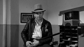 Movie still from “Paper Moon” (1973), directed by Peter Bogdanovich – A man wearing a hat and holding a baseball bat; Medium shot, Over the shoulder angle