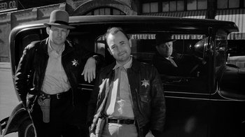 Movie still from “Paper Moon” (1973), directed by Peter Bogdanovich – A black and white photo of a man and a man in a car; Medium shot, Low angle