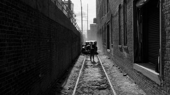 Movie still from “Paper Moon” (1973), directed by Peter Bogdanovich – A man walking down a narrow alley way; Extreme Wide shot, High angle