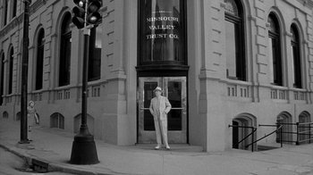 Movie still from “Paper Moon” (1973), directed by Peter Bogdanovich – A man standing in front of a large building; Wide shot, Low angle