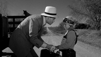 Movie still from “Paper Moon” (1973), directed by Peter Bogdanovich – A man and a boy holding hands on the side of a road; Medium shot, Over the shoulder angle