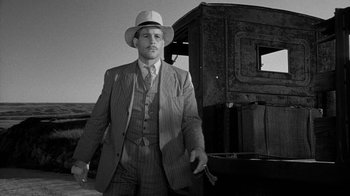 Movie still from “Paper Moon” (1973), directed by Peter Bogdanovich – A man in a suit and hat standing in front of an old train; Medium shot, Low angle