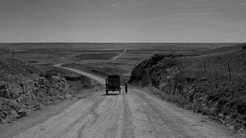 Movie still from “Paper Moon” (1973), directed by Peter Bogdanovich – A man standing next to a truck on the side of a dirt road; Extreme Wide shot, High angle