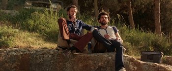 Movie still from “Paradise Now” (2005), directed by Hany Abu-Assad – A couple of men sitting next to each other on a rock; Medium shot, Low angle