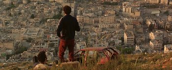 Movie still from “Paradise Now” (2005), directed by Hany Abu-Assad – A man standing on top of a hill looking over a city; Wide shot, High angle