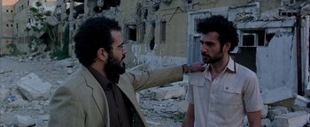 Movie still from “Paradise Now” (2005), directed by Hany Abu-Assad – Two men are standing in front of a destroyed building; Medium shot, Over the shoulder angle
