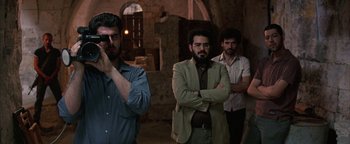 Movie still from “Paradise Now” (2005), directed by Hany Abu-Assad – A group of men standing next to each other in a room; Medium shot, Low angle