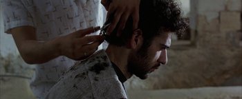 Movie still from “Paradise Now” (2005), directed by Hany Abu-Assad – A man getting his hair cut by a barber; Close Up shot, Over the shoulder angle