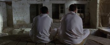 Movie still from “Paradise Now” (2005), directed by Hany Abu-Assad – A couple of men sitting next to each other on the ground; Wide shot, Low angle