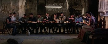 Movie still from “Paradise Now” (2005), directed by Hany Abu-Assad – A group of men sitting at a long dinner table; Wide shot, High angle