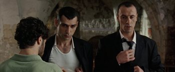 Movie still from “Paradise Now” (2005), directed by Hany Abu-Assad – A man in a white shirt and a man in a black suit; Close Up shot, Low angle