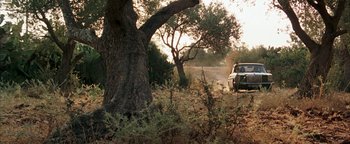 Movie still from “Paradise Now” (2005), directed by Hany Abu-Assad – A car driving down a dirt road next to a tree; Extreme Wide shot, Low angle