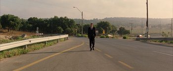 Movie still from “Paradise Now” (2005), directed by Hany Abu-Assad – A man in a suit is walking down the street; Wide shot, Low angle