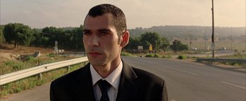 Movie still from “Paradise Now” (2005), directed by Hany Abu-Assad – A person wearing a suit and tie near a road; Close Up shot, Low angle